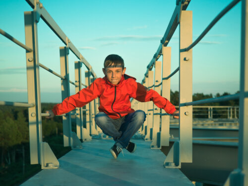 parkour niño sentado en el puente de hierro puerto de fondo