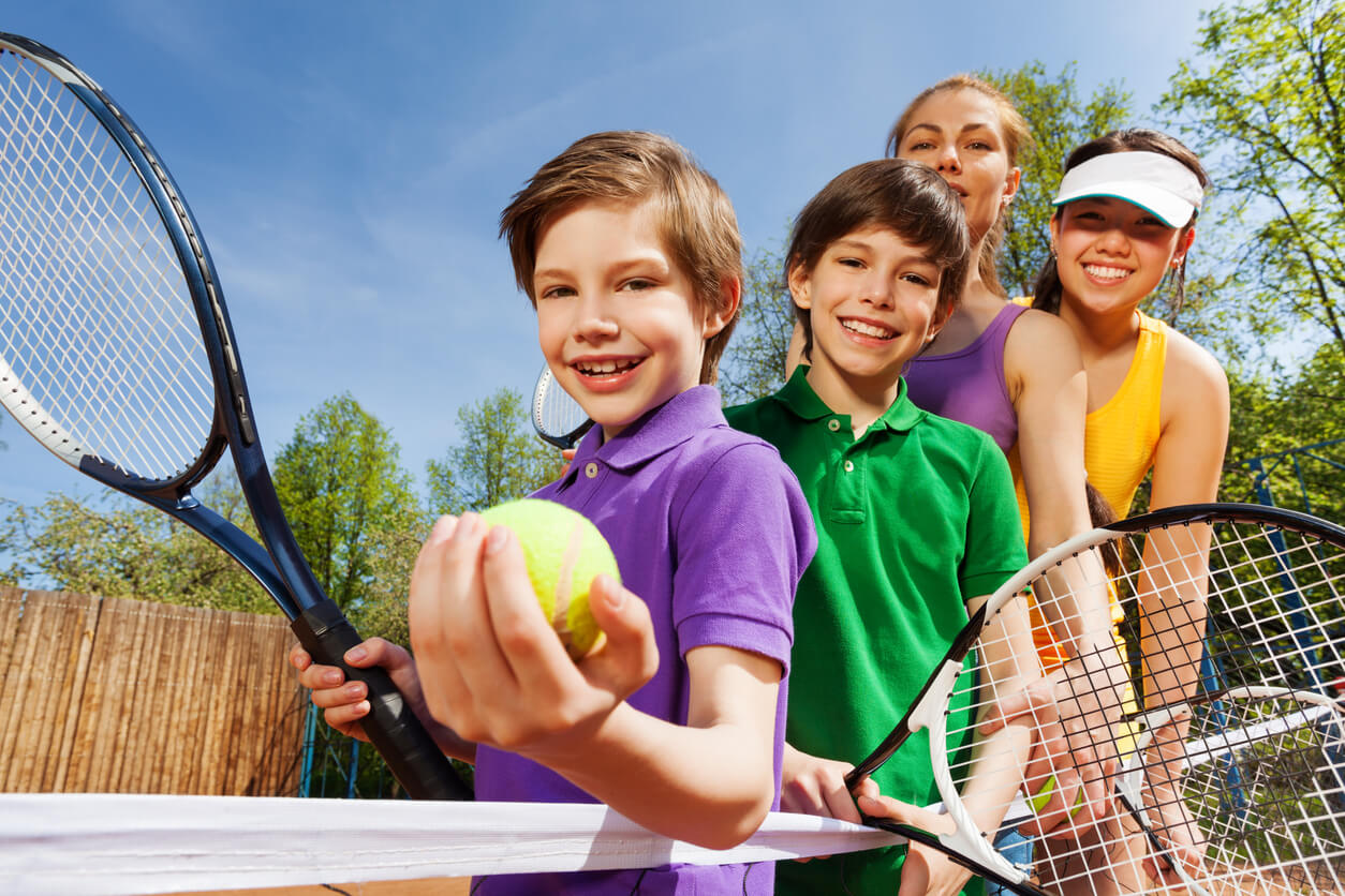 4 ninos felices en la cancha de tenis