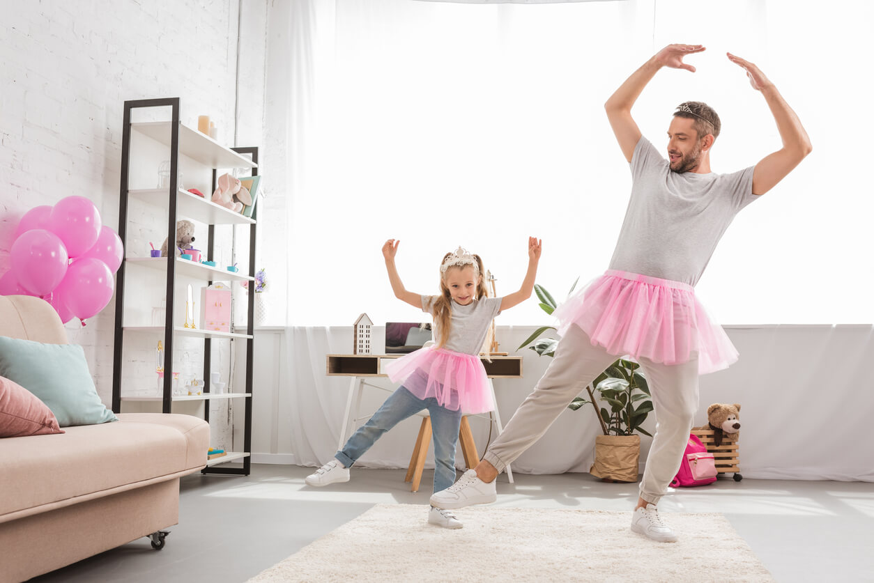 A falther and daughter wearing tutus and dancing ballet in their home.