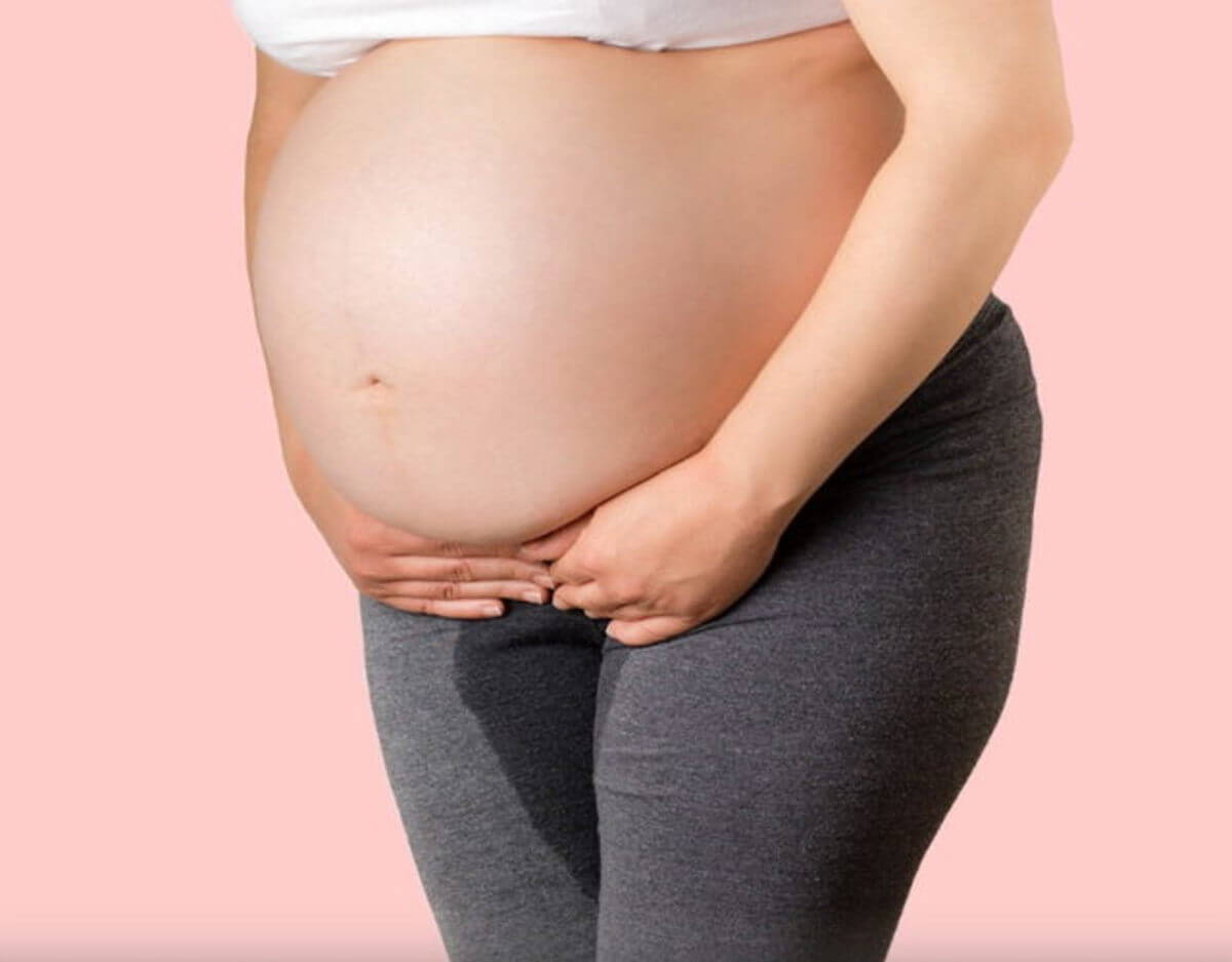 mujer embarazada de pie pierde liquido amniotico entre las piernas