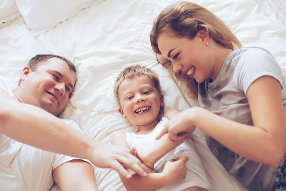 Niño feliz durmiendo con sus padres