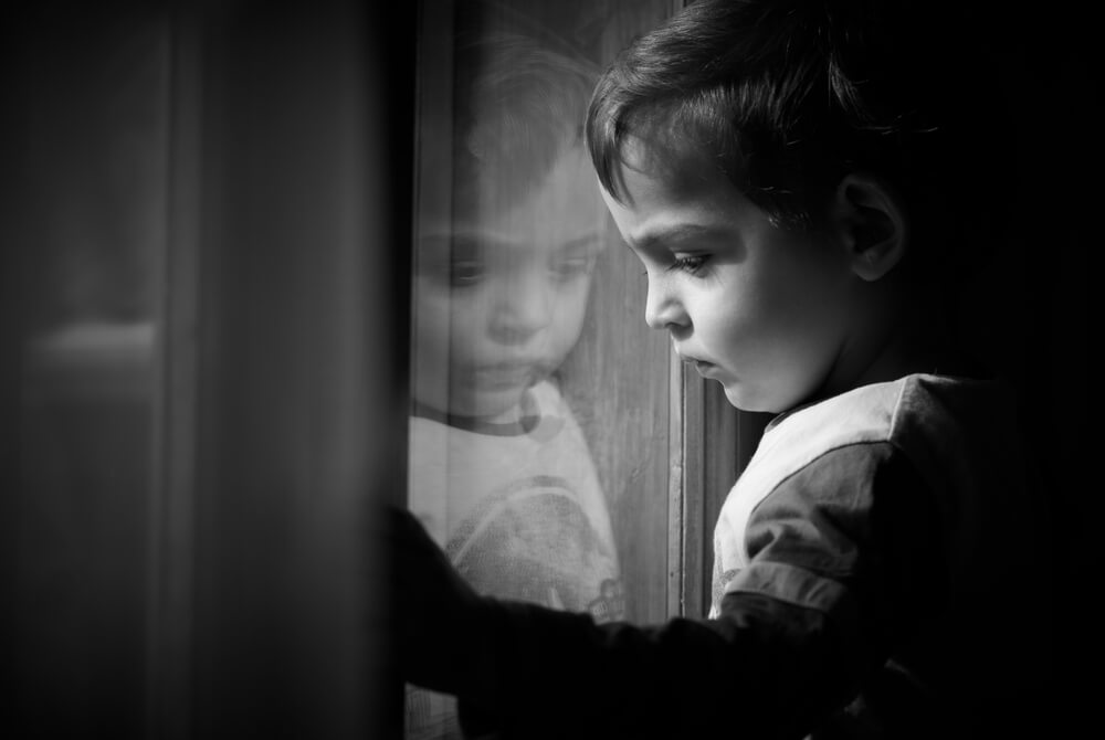 Un enfant qui regarde à travers une fenêtre.
