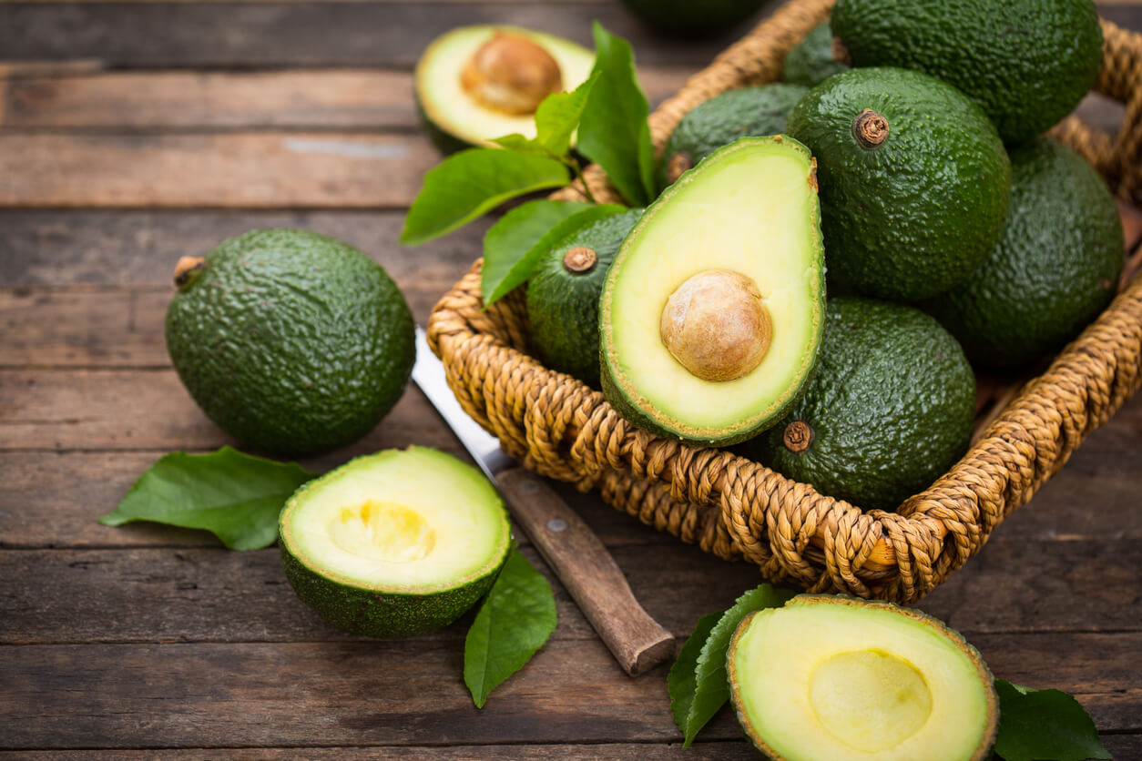 avocats mûrs tranchés sur un panier de table en bois
