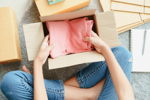 mujer coloca ropa en caja de carton archiva