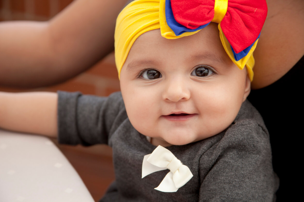 bébé regarde l'accessoire pour cheveux de l'appareil photo aux couleurs de la colombie rouge jaune bleu