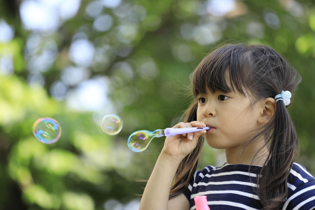 ragazza soffia bolle nel parco delle lampadine