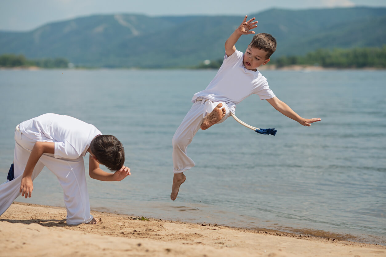 Deux enfants qui font de la capoeira sur la plage. 