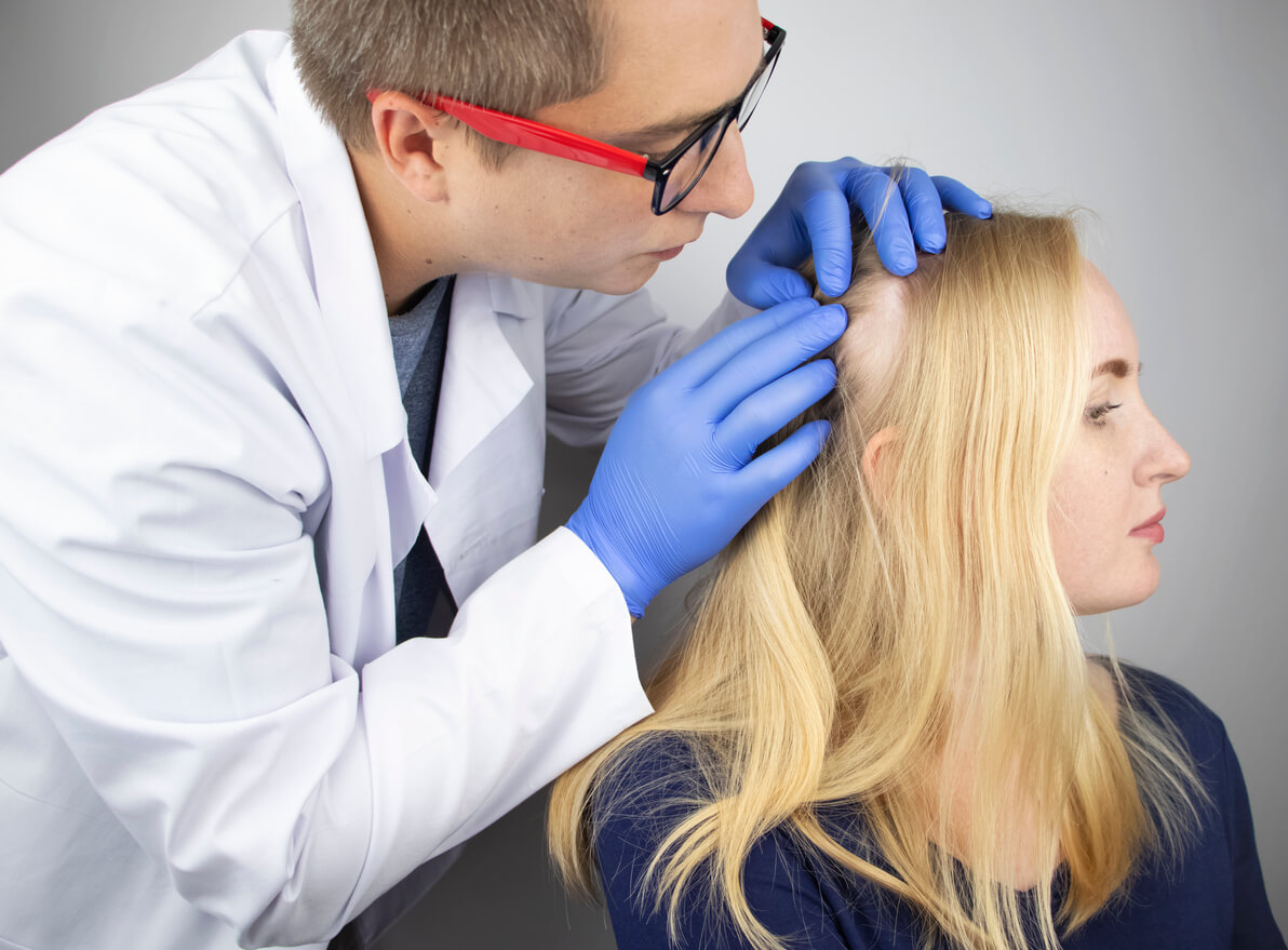 un dermatologue évalue la plaque d'alopécie du cuir chevelu dans les cheveux d'une adolescente