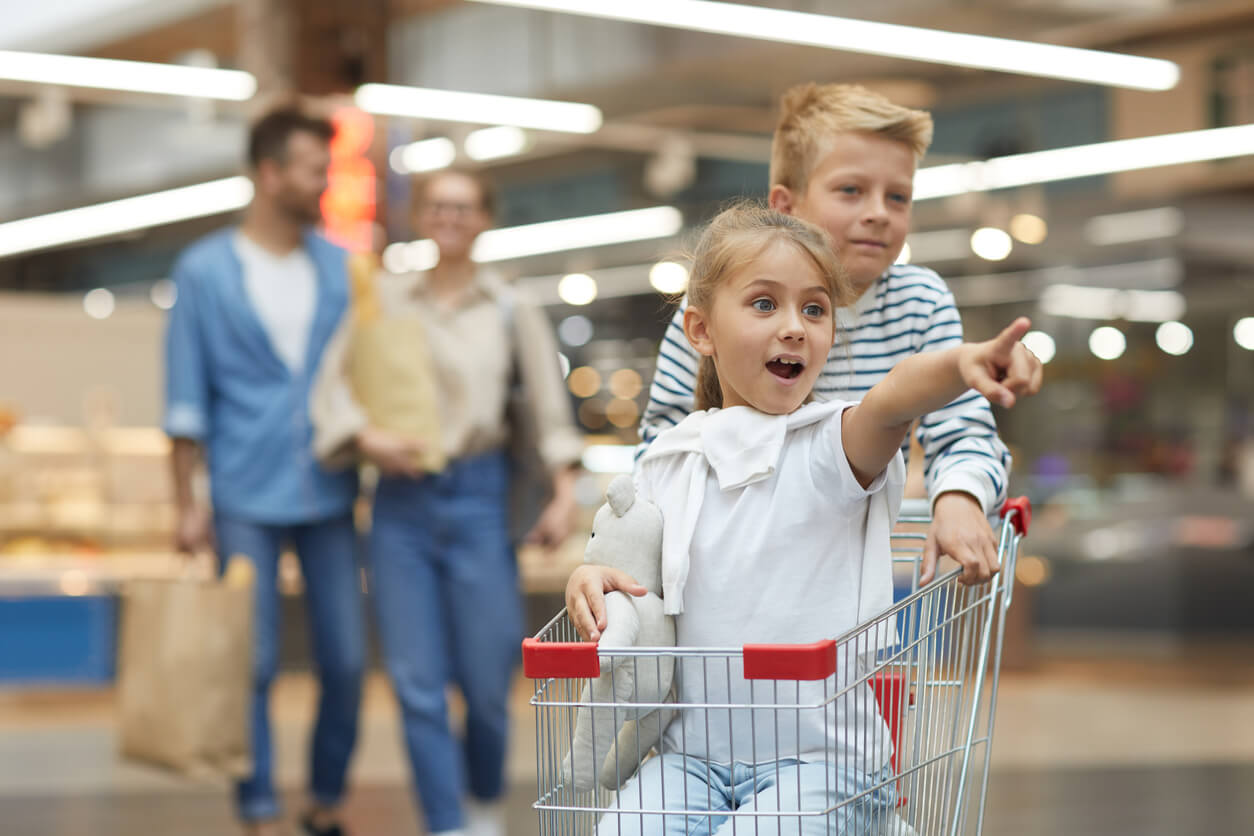 ninos en el carro de supermercado compras en familia padres cargan bolsas de fondo