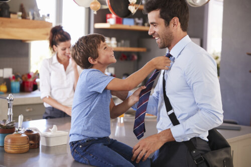 hijo le arregla la corbata al padre antes de irse al trabajo felices saludos