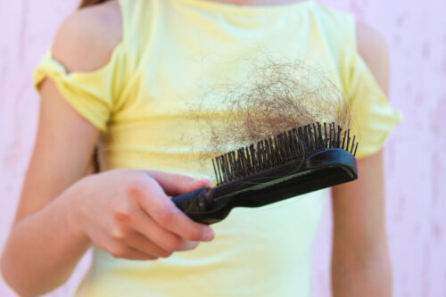 chica joven con cepillo de pelo en mano con perdida caida de cabello