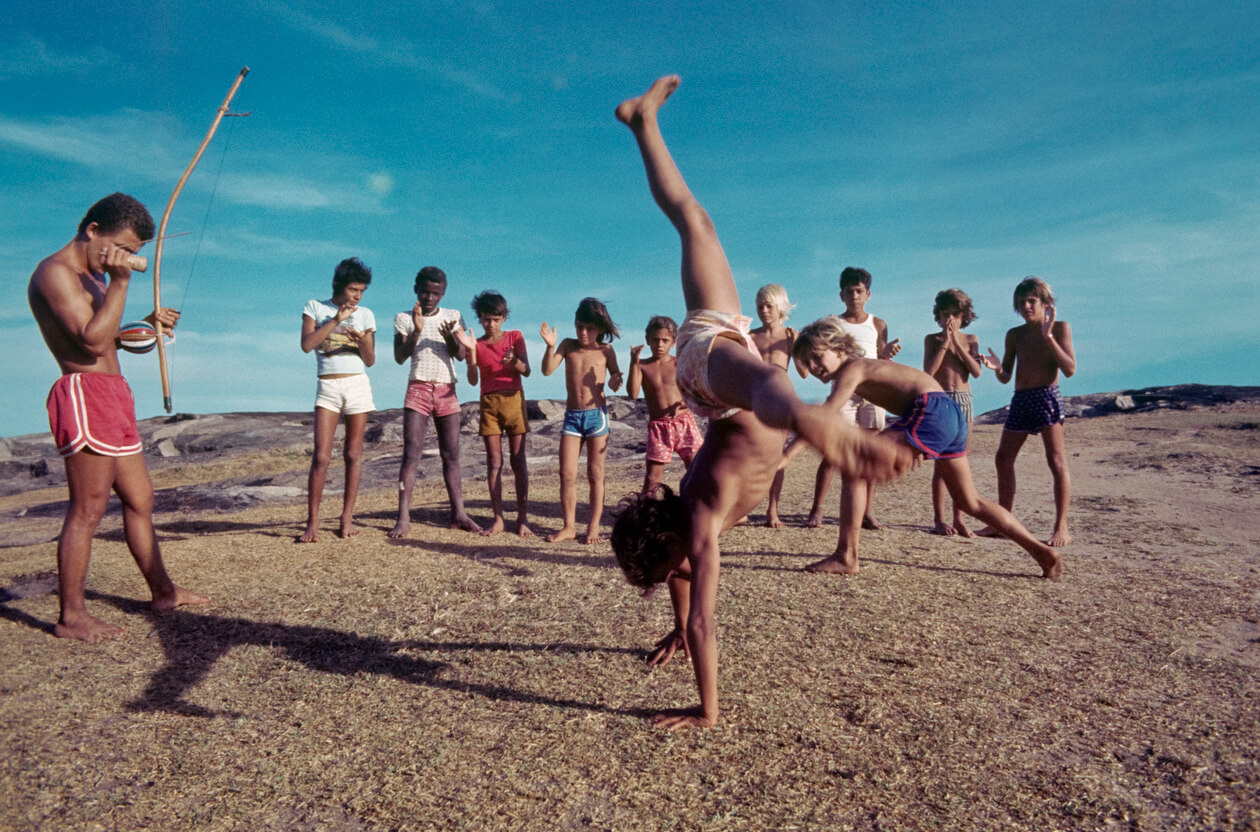 Barn på stranden lærer capoeira med en lærer.