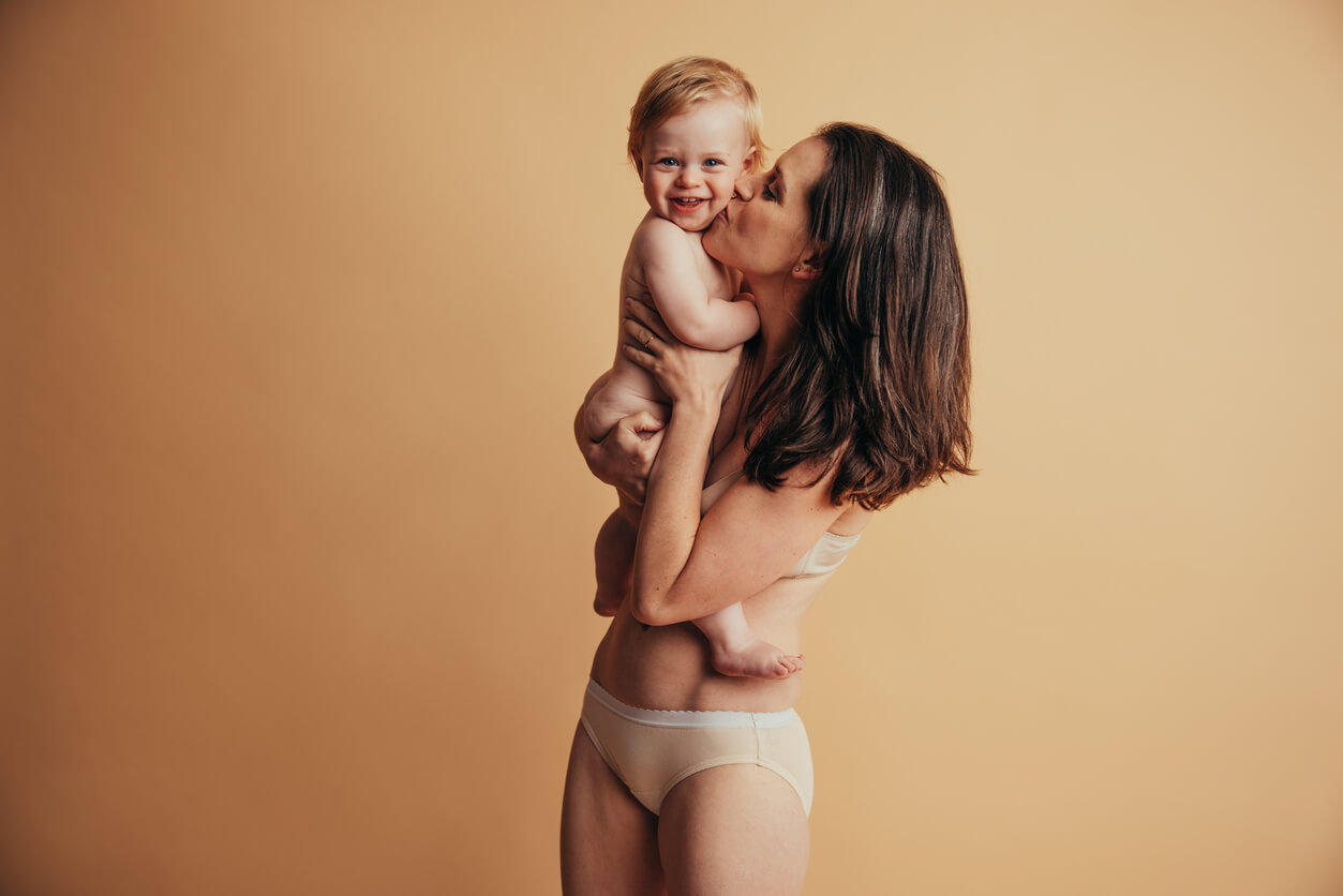 A mother kissing her baby boy on the cheek.