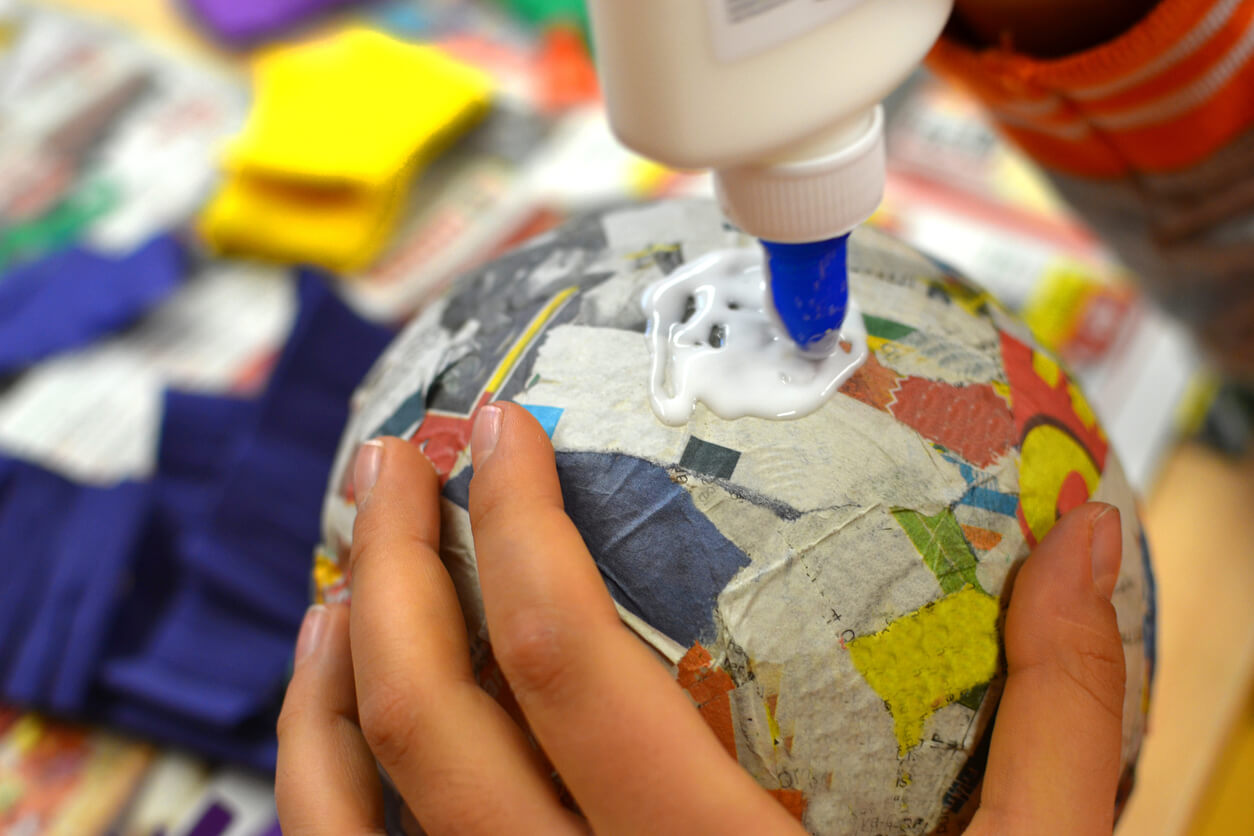 A girl making a paper mache ball.