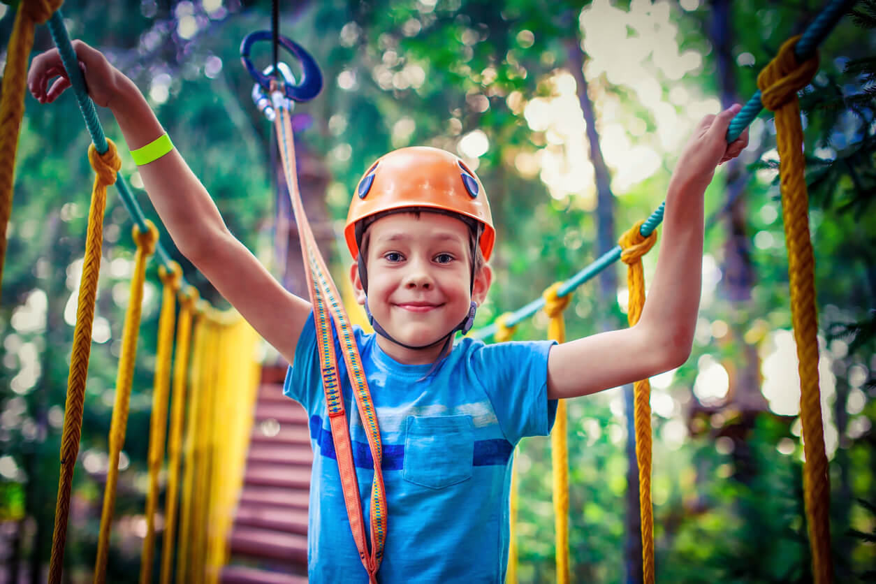 A child crosses hanging bridge at an adventure park.