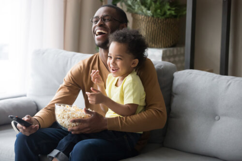 padre e hijo en el sillon sentados miran peliculas y comen palomitas