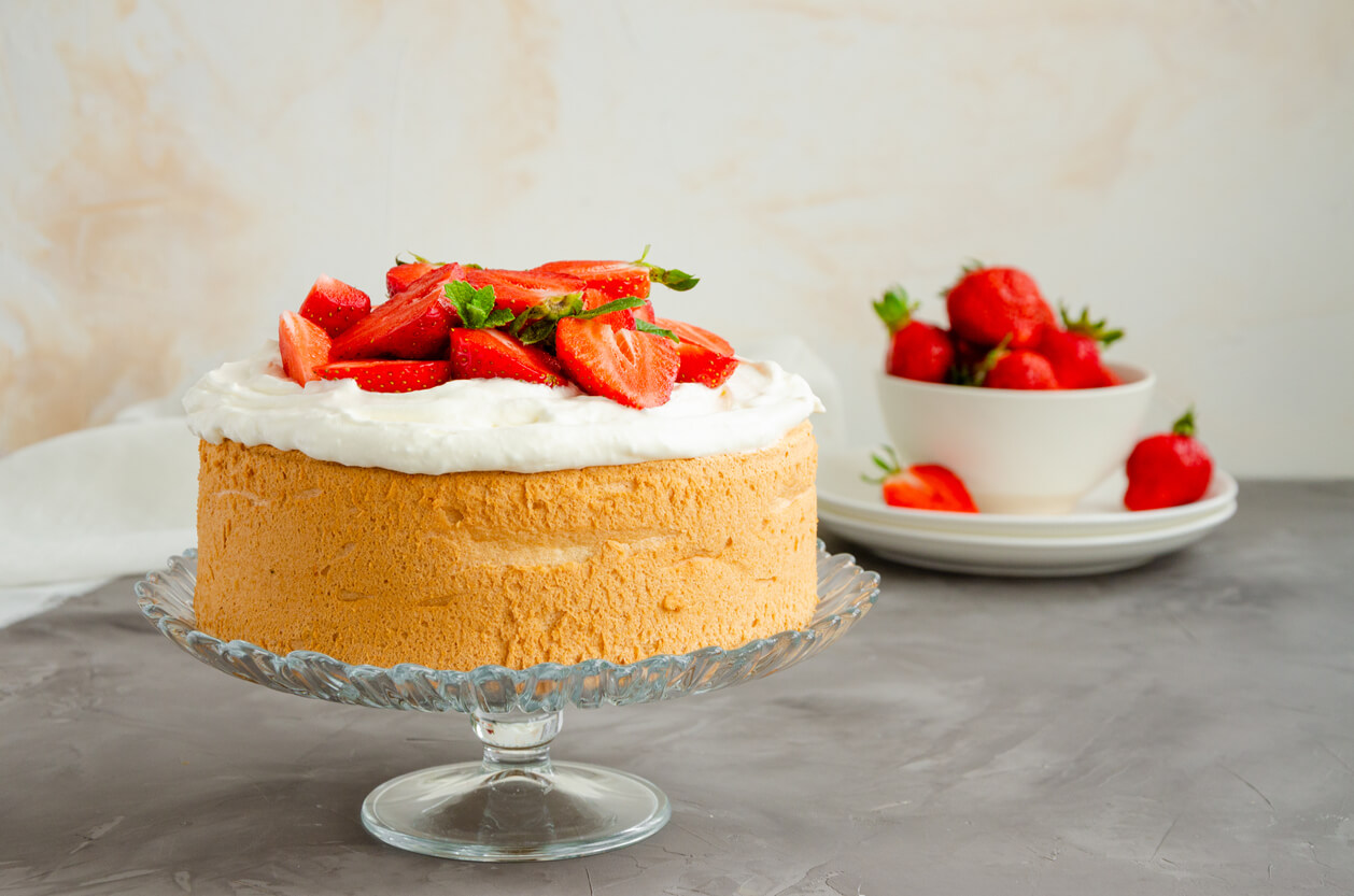 A cake topped with whipped cream and strawberries.