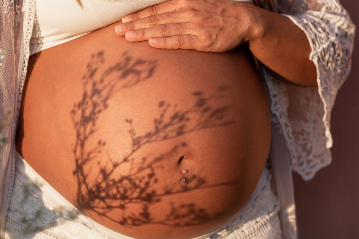 Sombra de uma planta refletindo na barriga barriga de uma mulher grávida.