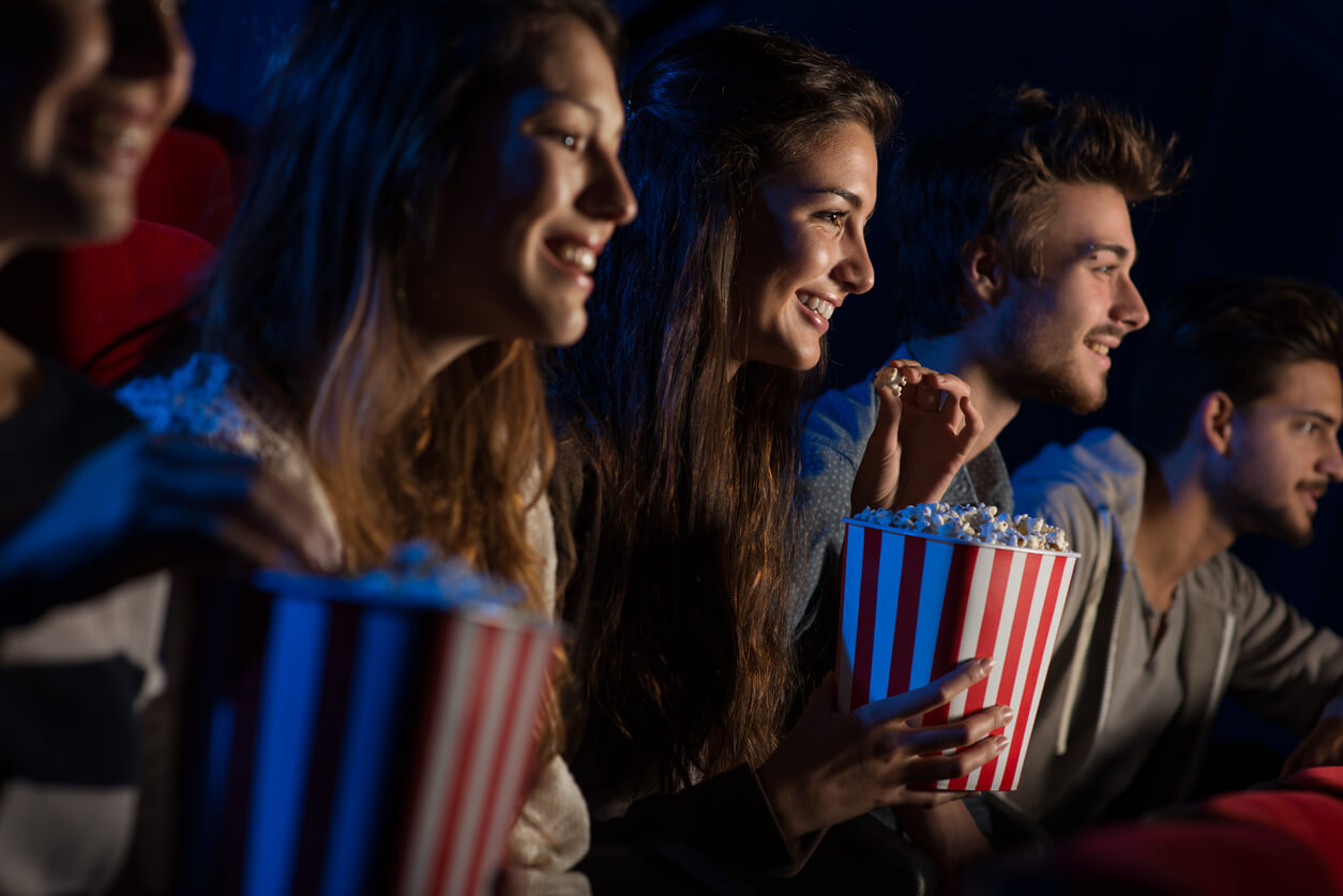 Teenagers eating popcorn at the movie theater.