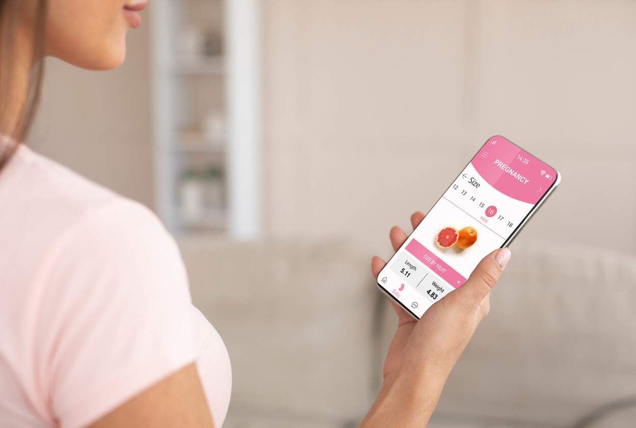 Une femme qui regarde une application de grossesse sur son téléphone.