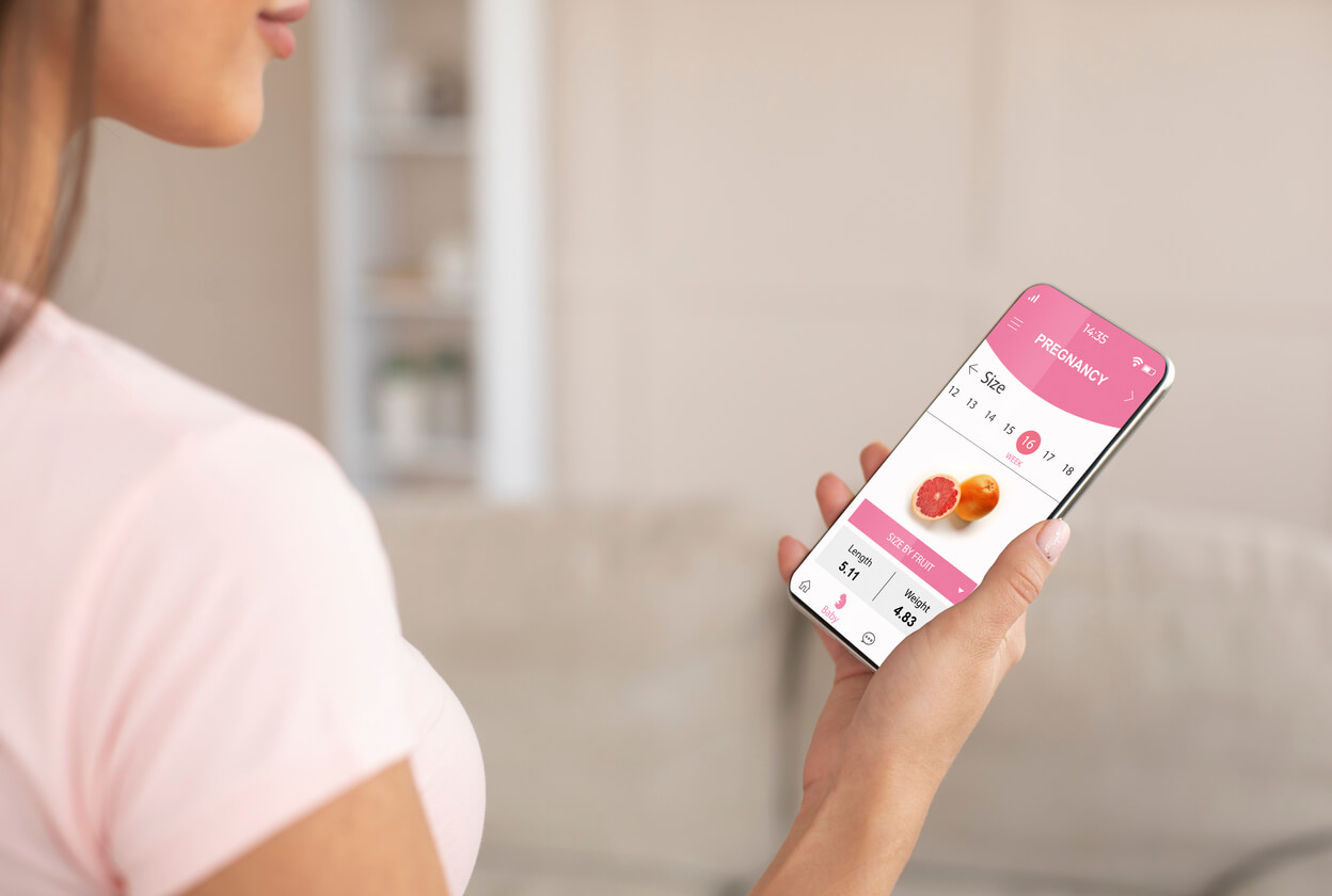 madre movil en mano con app aplicacion embarazo bebe tamano pomelo