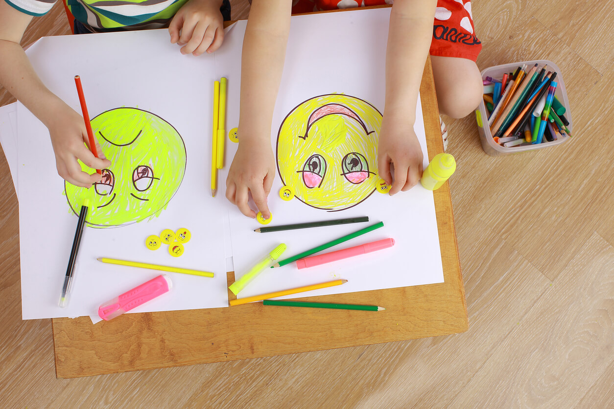 Small children drawing emojis.