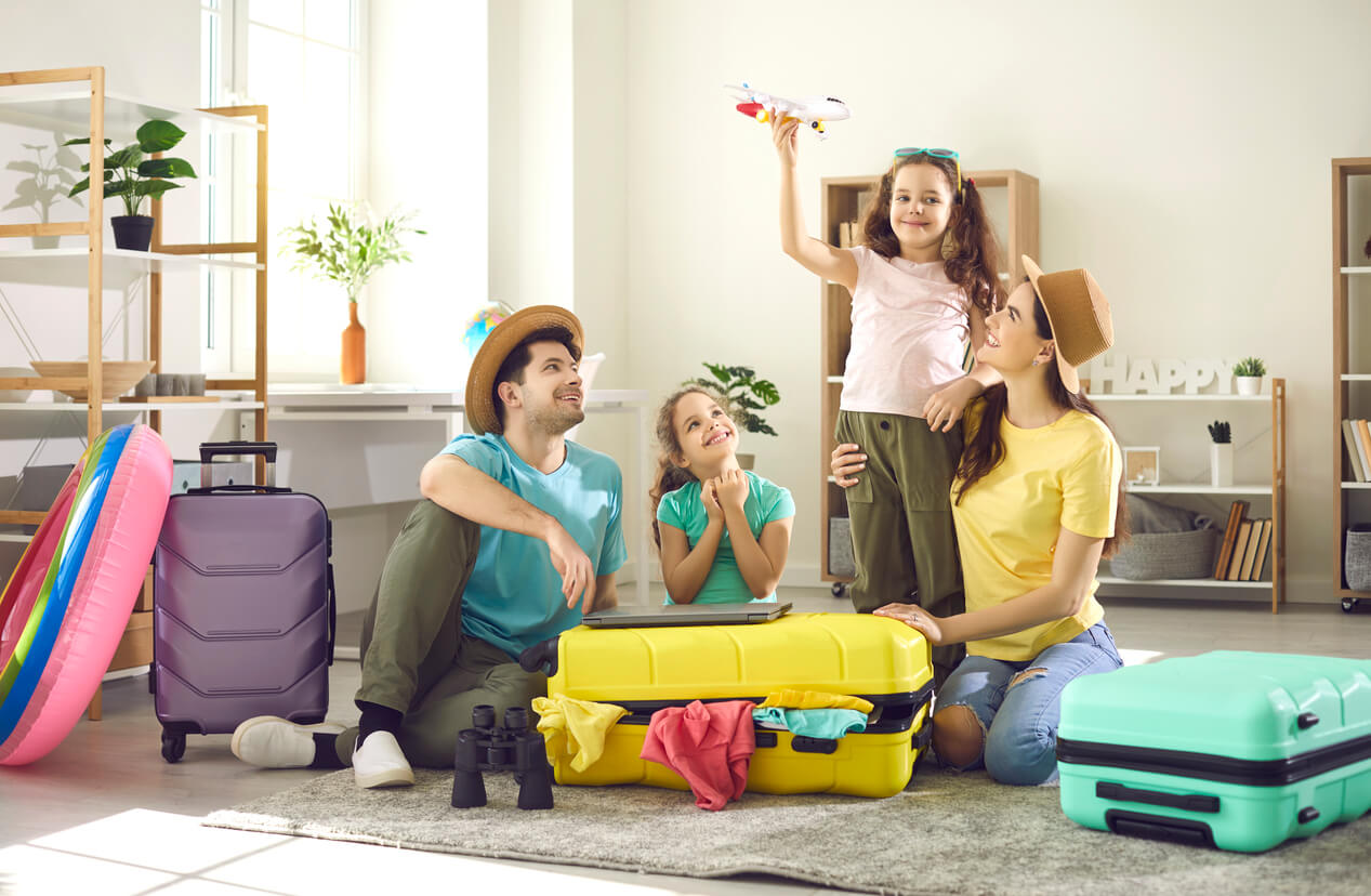familia sentada en la sala de la casa con el equipaje de las vacaciones maletas