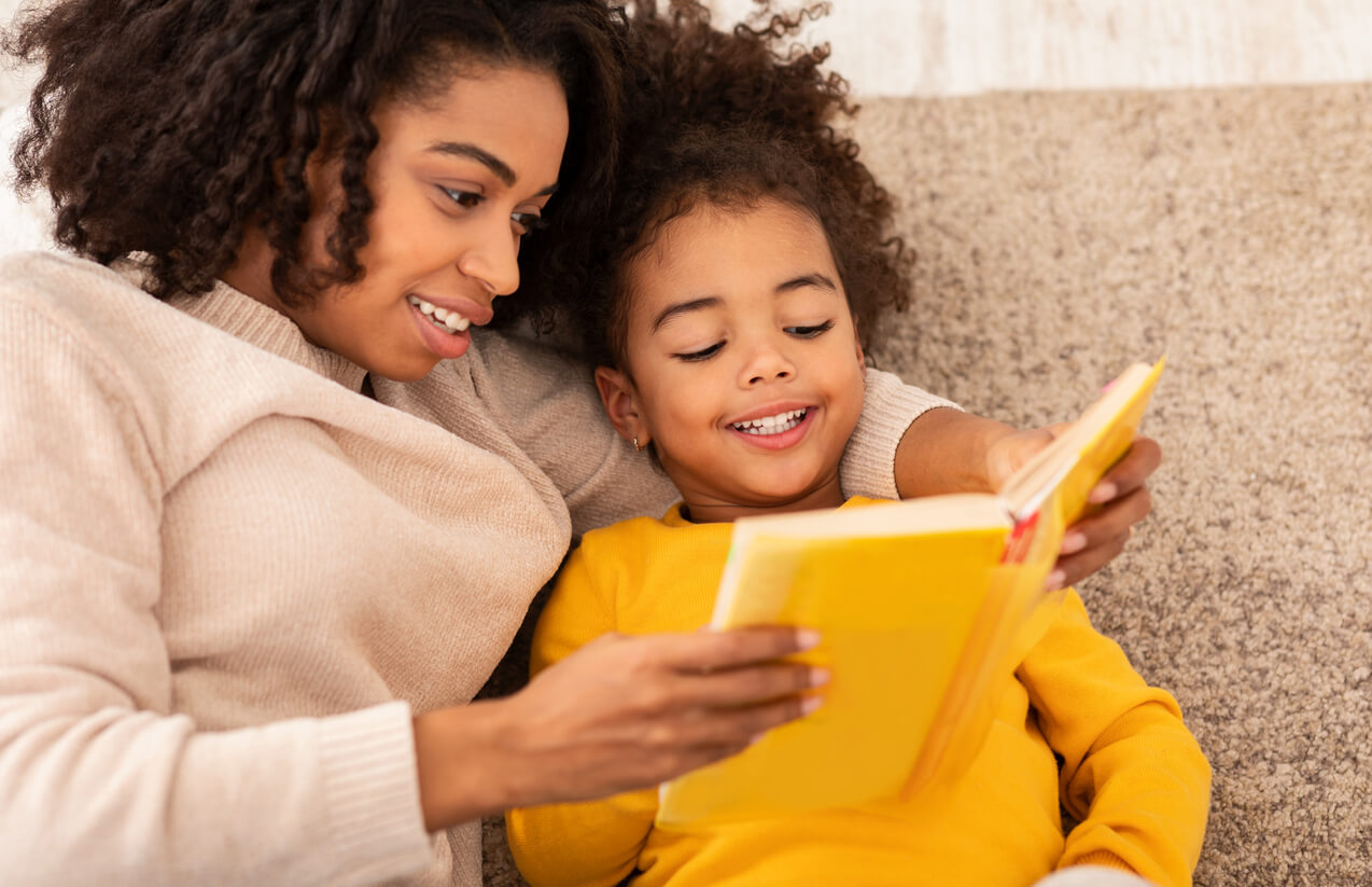 madre e hija leen libro juntas en el sofa sillon