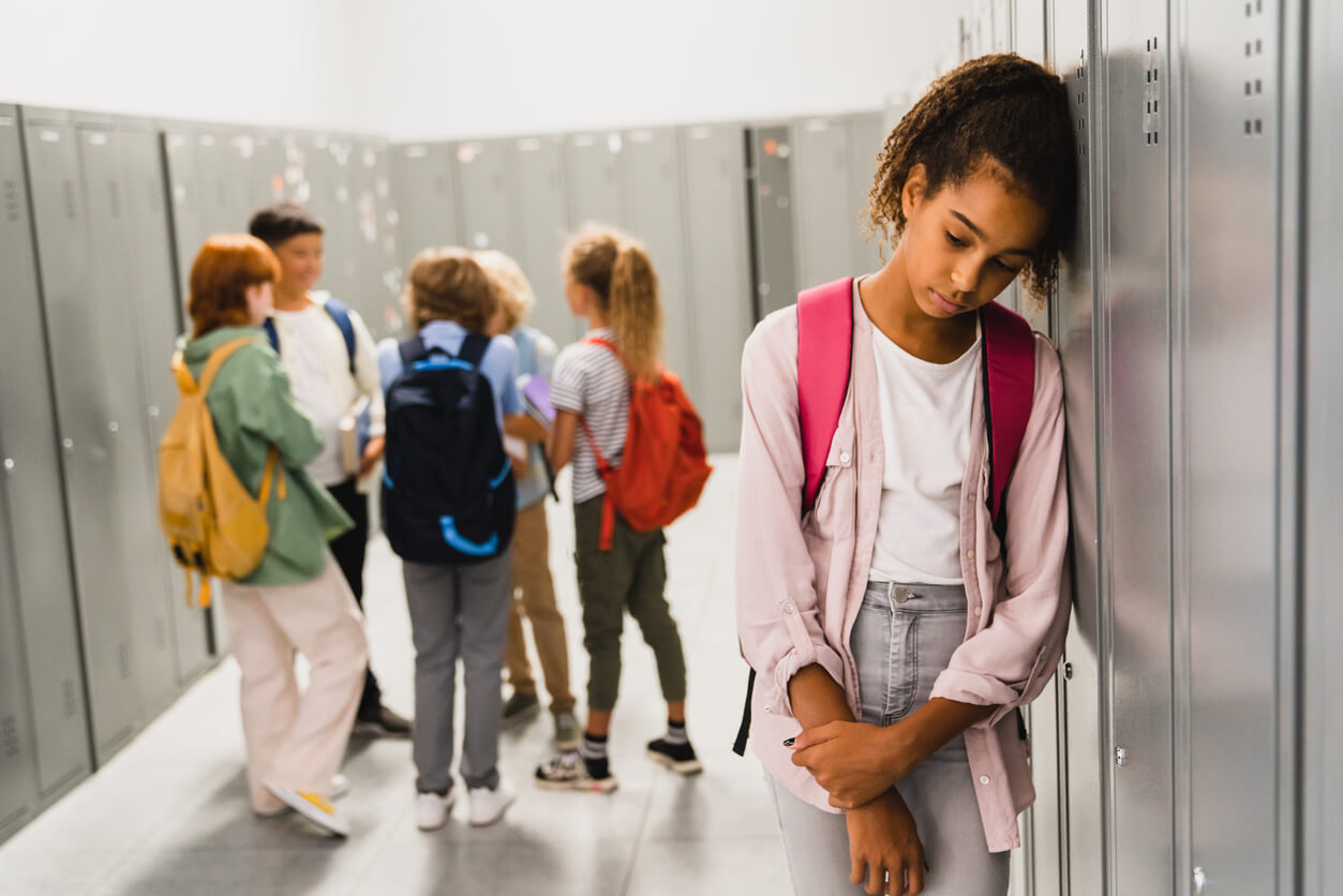 nina aislada por sus pares en el pasillo de la escuela tristeza exclusion bullying acoso escolar