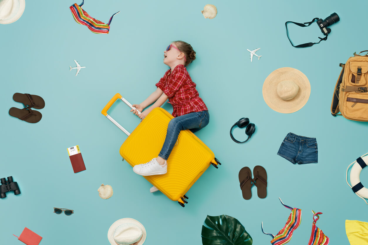 An image of a girl riding a suitcase in the air, surrounded by vacation items.