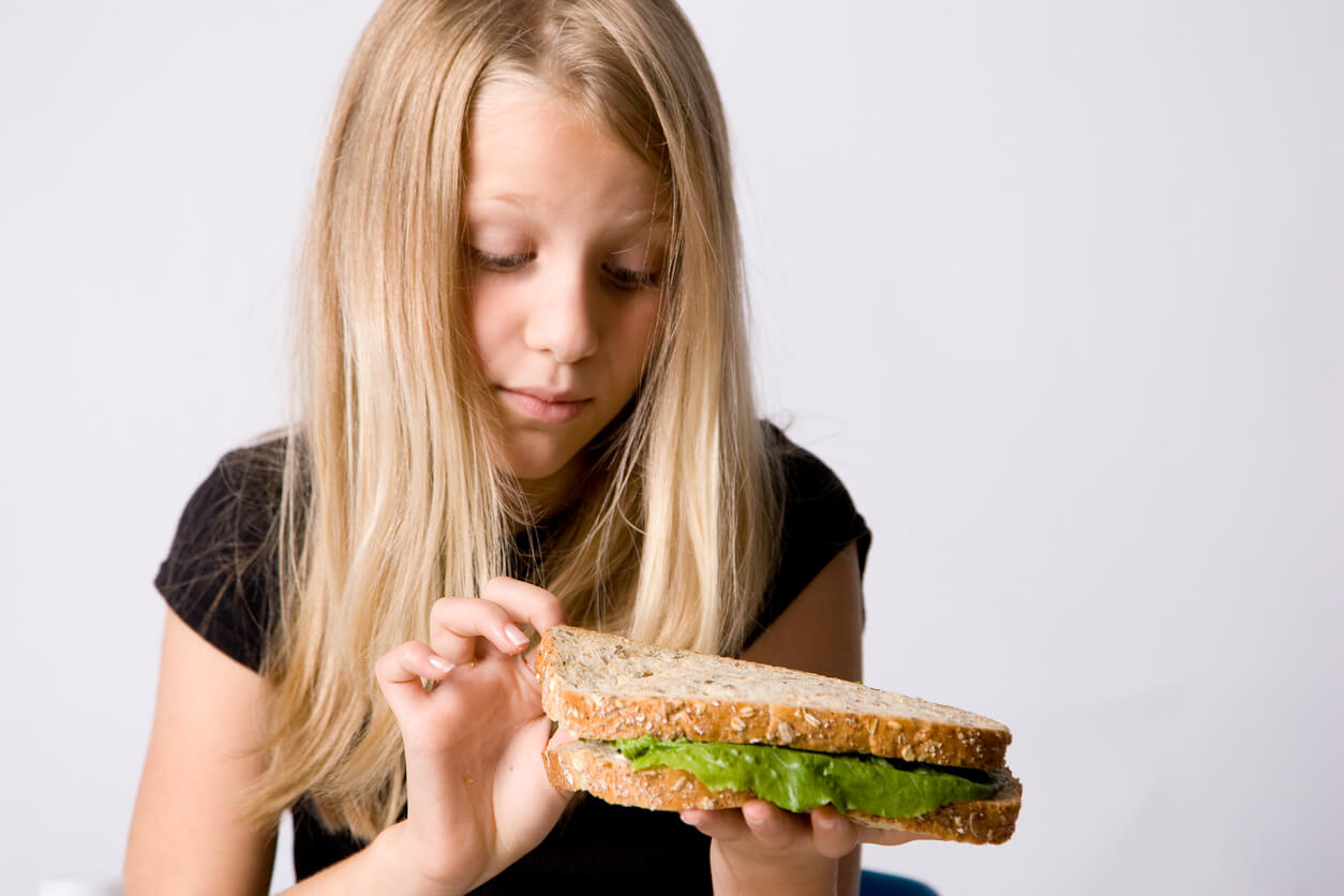 nina hiper selectiva con la comida rechaza comestibles del sandwich alimento emparedado lechuga pan integral