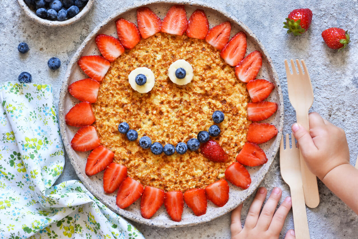 En pannekake dekorert med frukt for å se ut som en smilende blomst