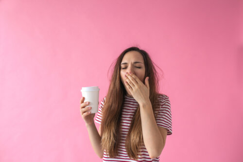 adolescene con vaso de cafe en mano bosteza sueno cansancio