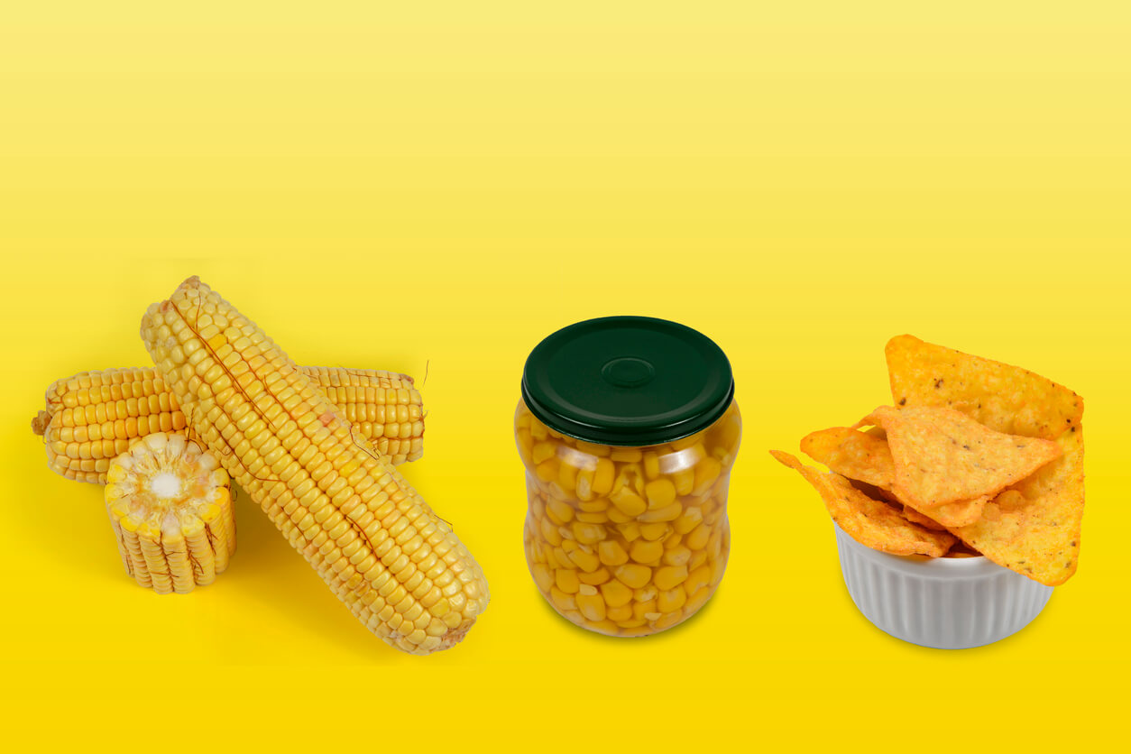 Corn on the cob, corn kernels in a jar, and corn-based tortilla chips.