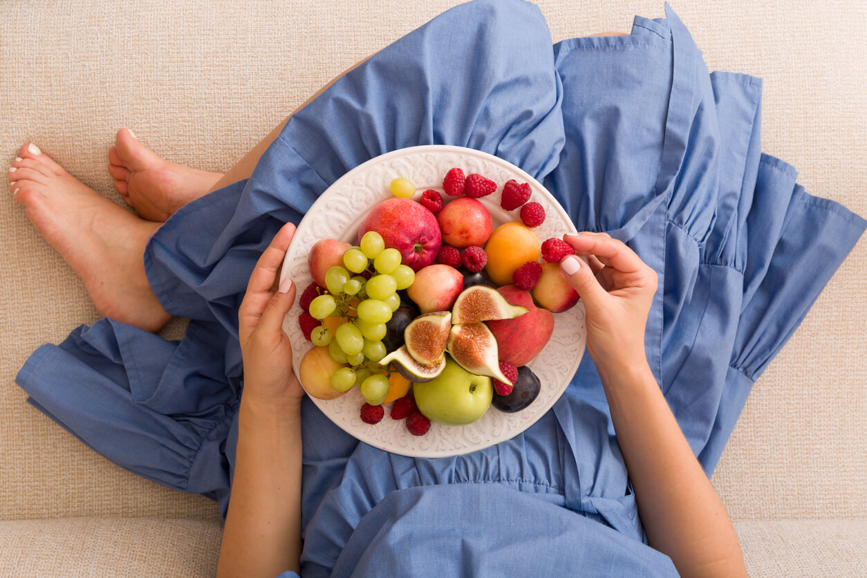 A pregnant woman eating fresh fruit.