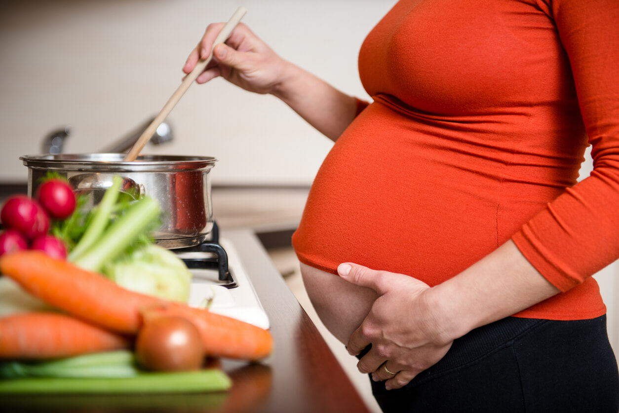 Une femme enceinte qui cuisine.