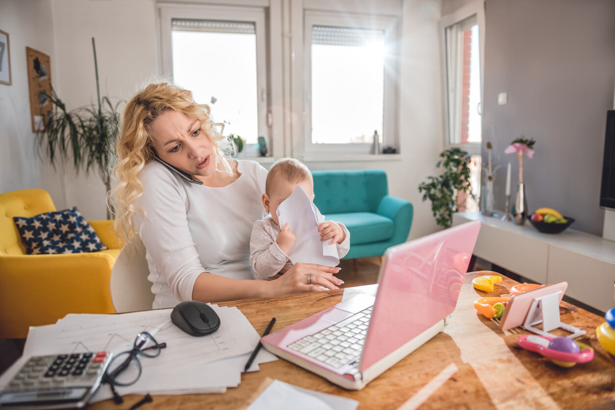A mother working from home with a baby on her lap.