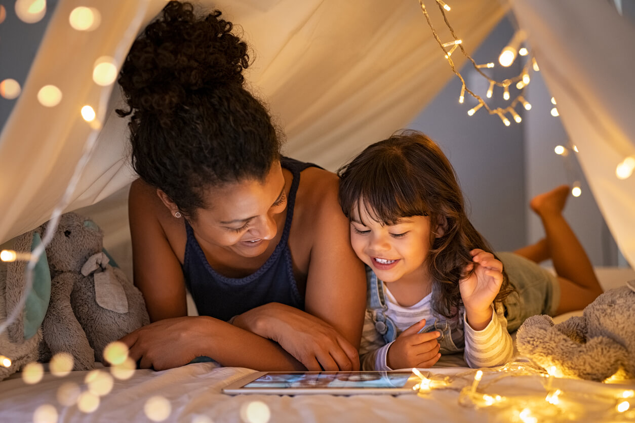Une maman et sa fille qui joue ensemble sous une tente.
