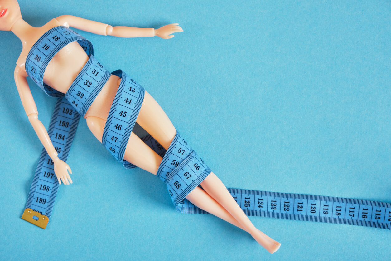 A barbie wrapped in measuring tape.