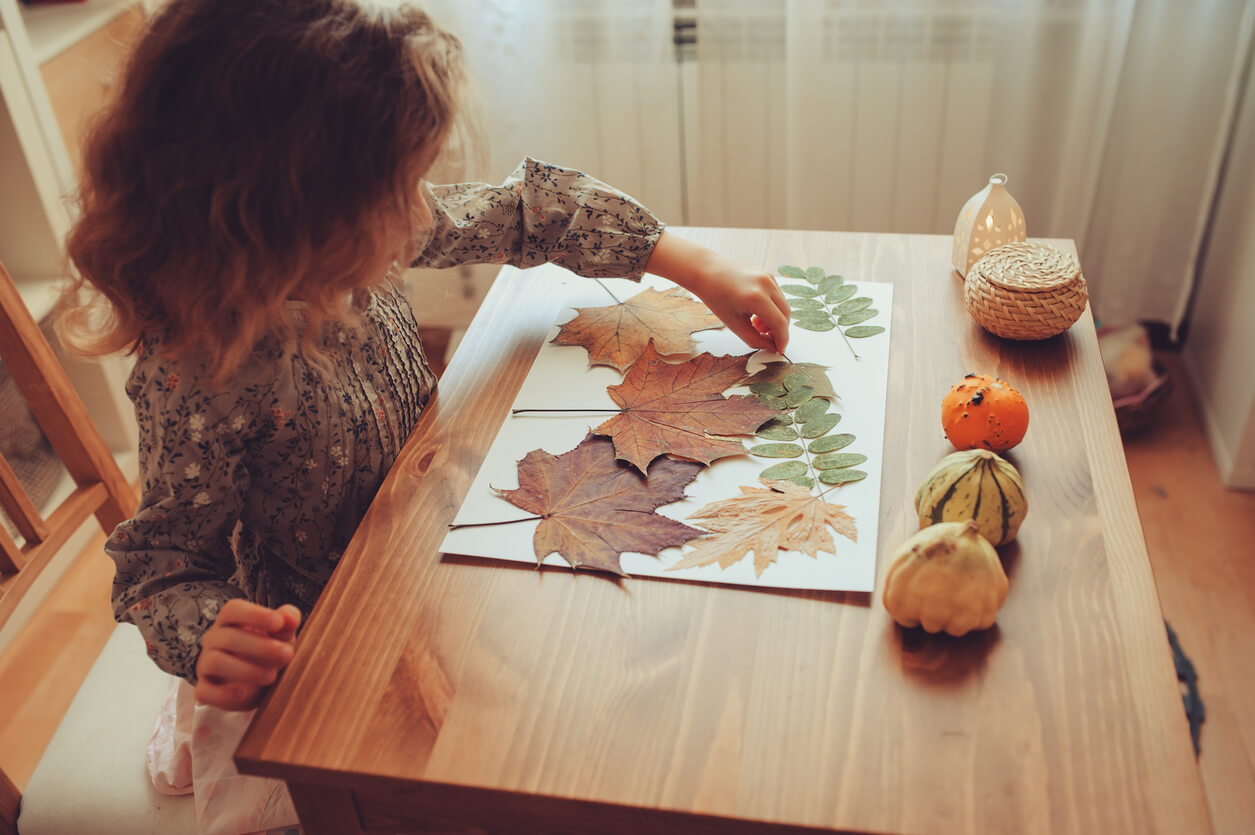 A child arranging dry leaves on paper.