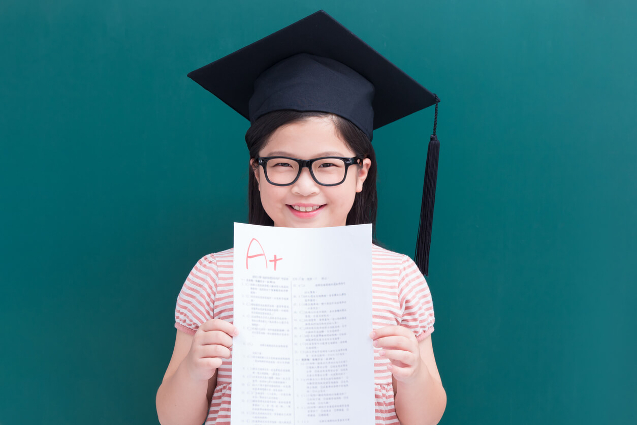 nina feliz sostiene examen con calificacion sobresaliente a+