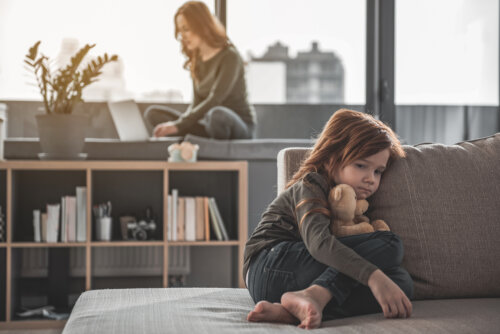 madre trabaja con computadora nino triste en el sofa con su oso apatia soledad