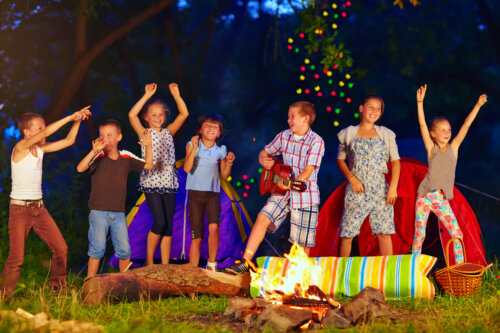 ninos felices cantan y bailan en la hoguera campamento de verano