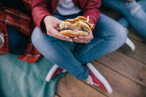 joven adolescente come hamburguesa completa en la mano