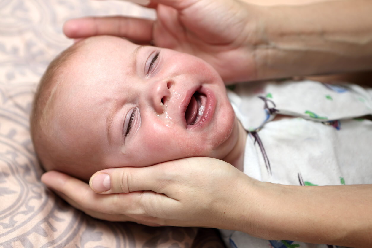 A baby crying with a runny nose.
