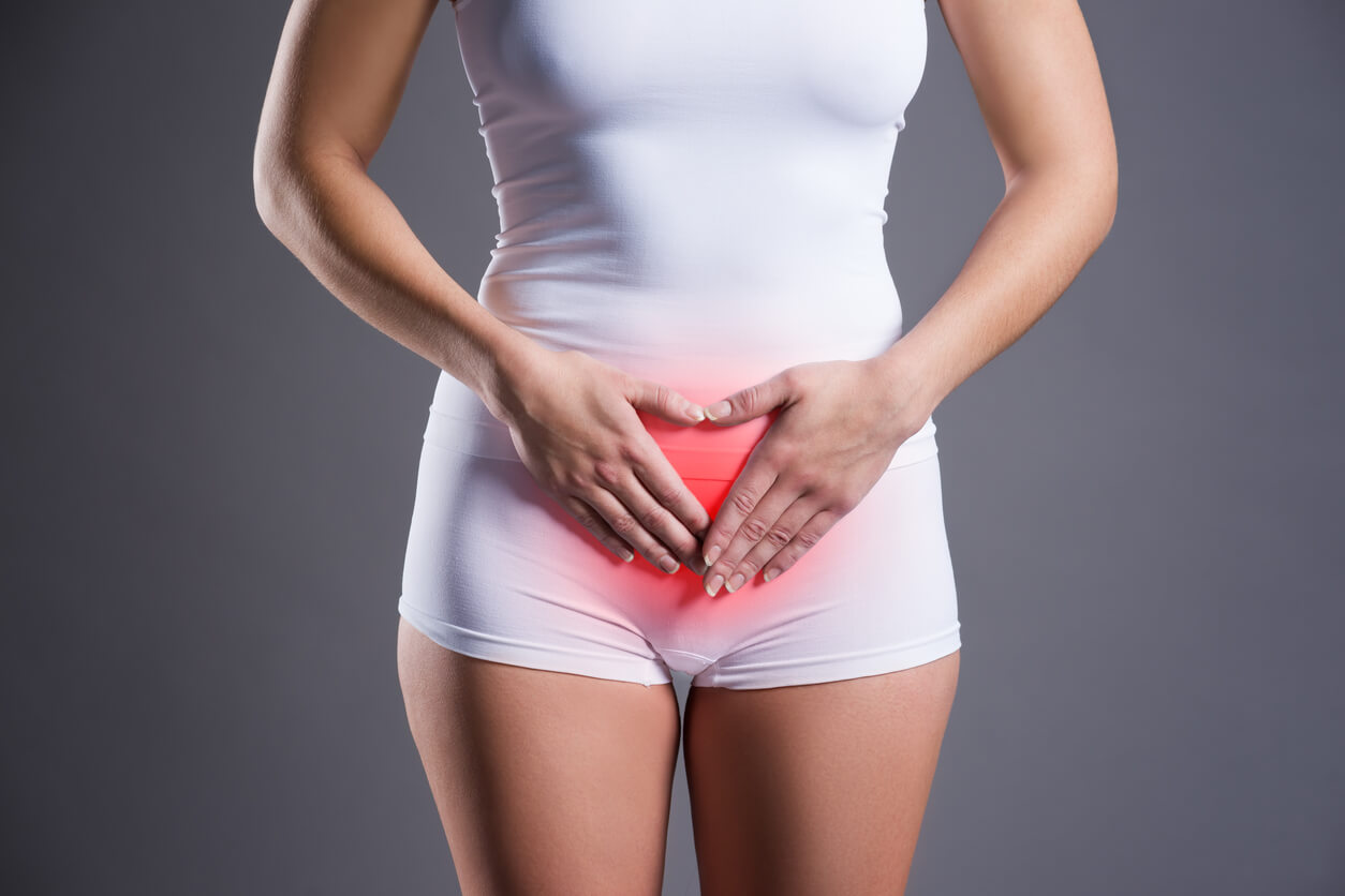 A woman with her hands over her abdomen.