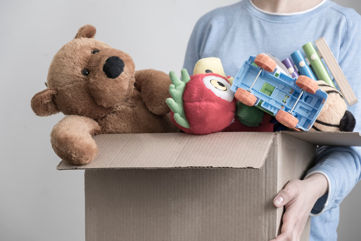 A child carrying his belongings in a cardboard box.