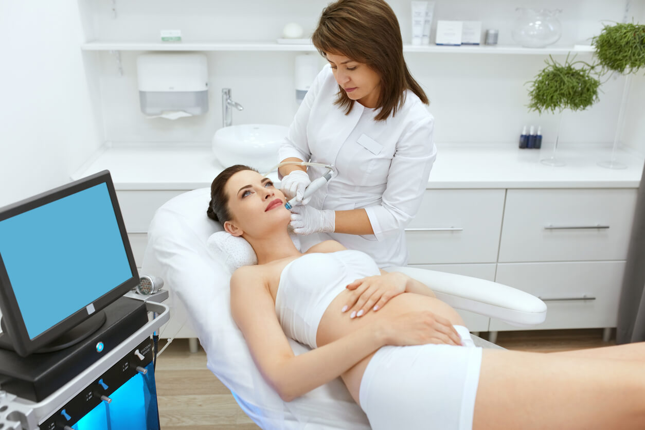 En gravid kvinne som gjennomgår profesjonell hudeksfoliering i ansiktet.