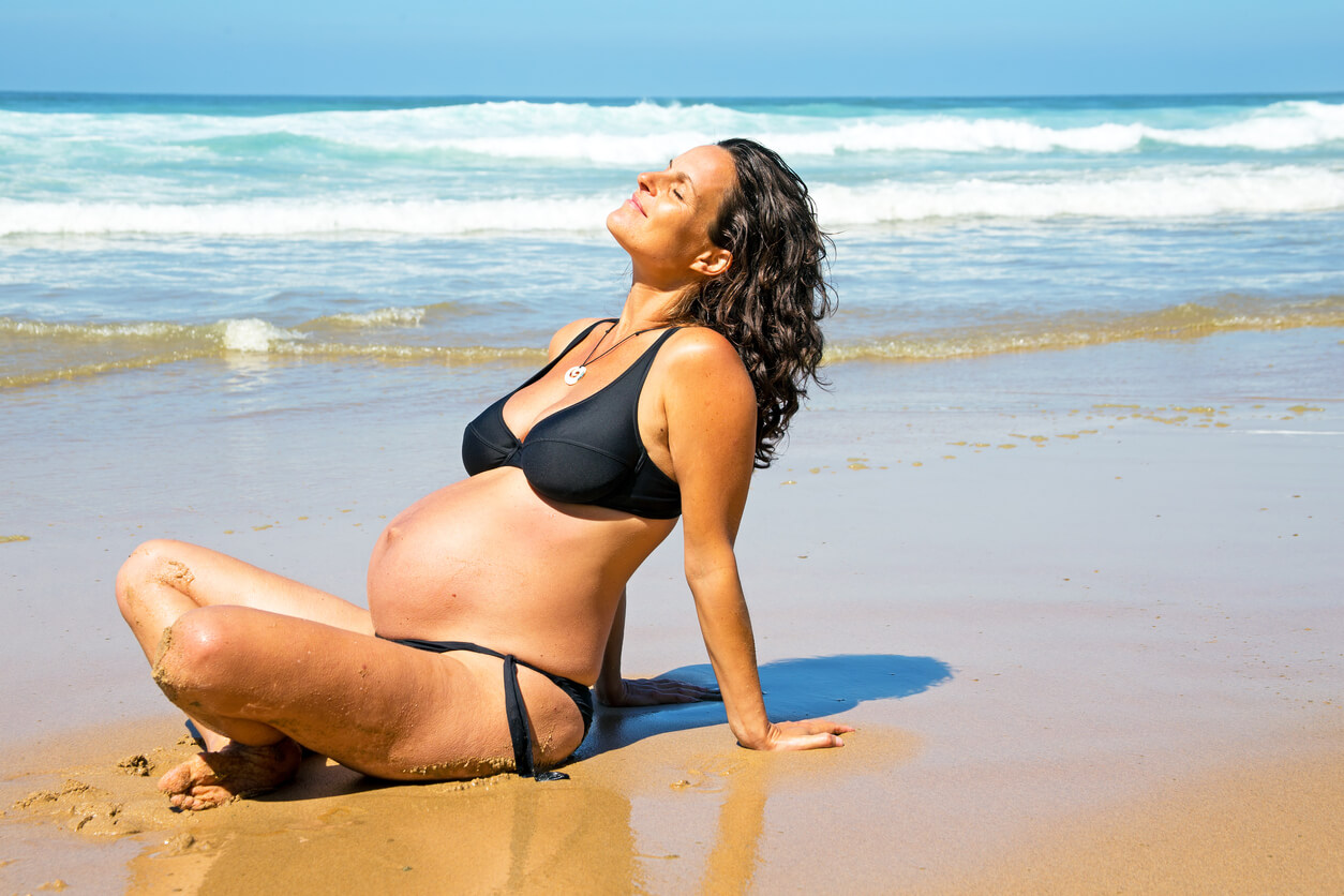 mujer embarazada toma sol en la playa