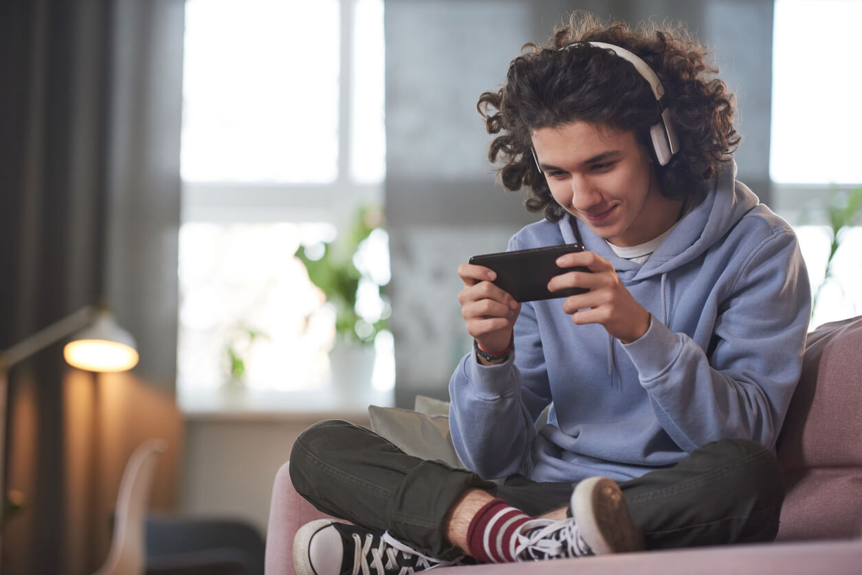 A teenager using a cell phone and listening to headphones.